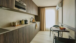 Una cocina moderna con armarios de madera, horno empotrado y un comedor con mesa y sillas.