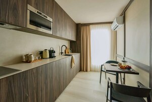 A modern kitchen with wooden cabinetry, a built-in oven, and a dining area with a table and chairs.