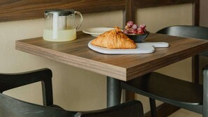 Una mesa con un croissant, un bol de uvas y una jarrón con leche.