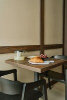 A table with a croissant, a bowl of grapes, and a glass pitcher of milk.