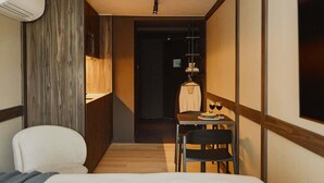 Una habitación de hotel con una cama, un escritorio con silla, una lámpara colgante y un armario.