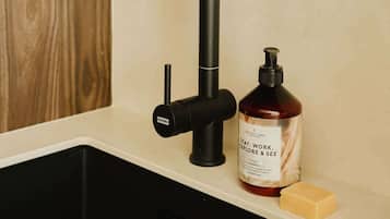A modern kitchen sink with a black faucet, a soap dispenser, and a bar of soap.