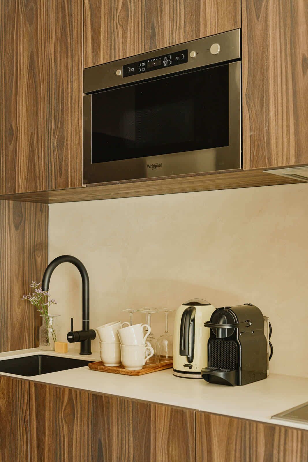A modern kitchen with a built-in stainless steel Whirlpool oven, a black faucet, and a coffee maker on the countertop.