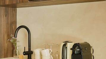 A modern kitchen with a built-in stainless steel Whirlpool oven, a black faucet, and a coffee maker on the countertop.