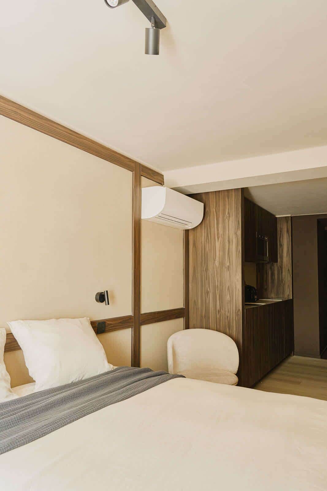 Une chambre d’hôtel moderne, équipée d’un lit, d’une chaise et d’une armoire intégrée.