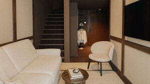 Ein modernes Wohnzimmer mit einer Couch, einem runden Couchtisch, einem Sessel und einem Fernseher.