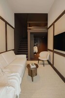 A modern living room with a sofa, a round coffee table, a chair, and a TV.