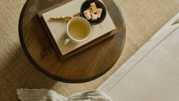 A round wooden table with a white mug, a small bowl of cubes, and a book.