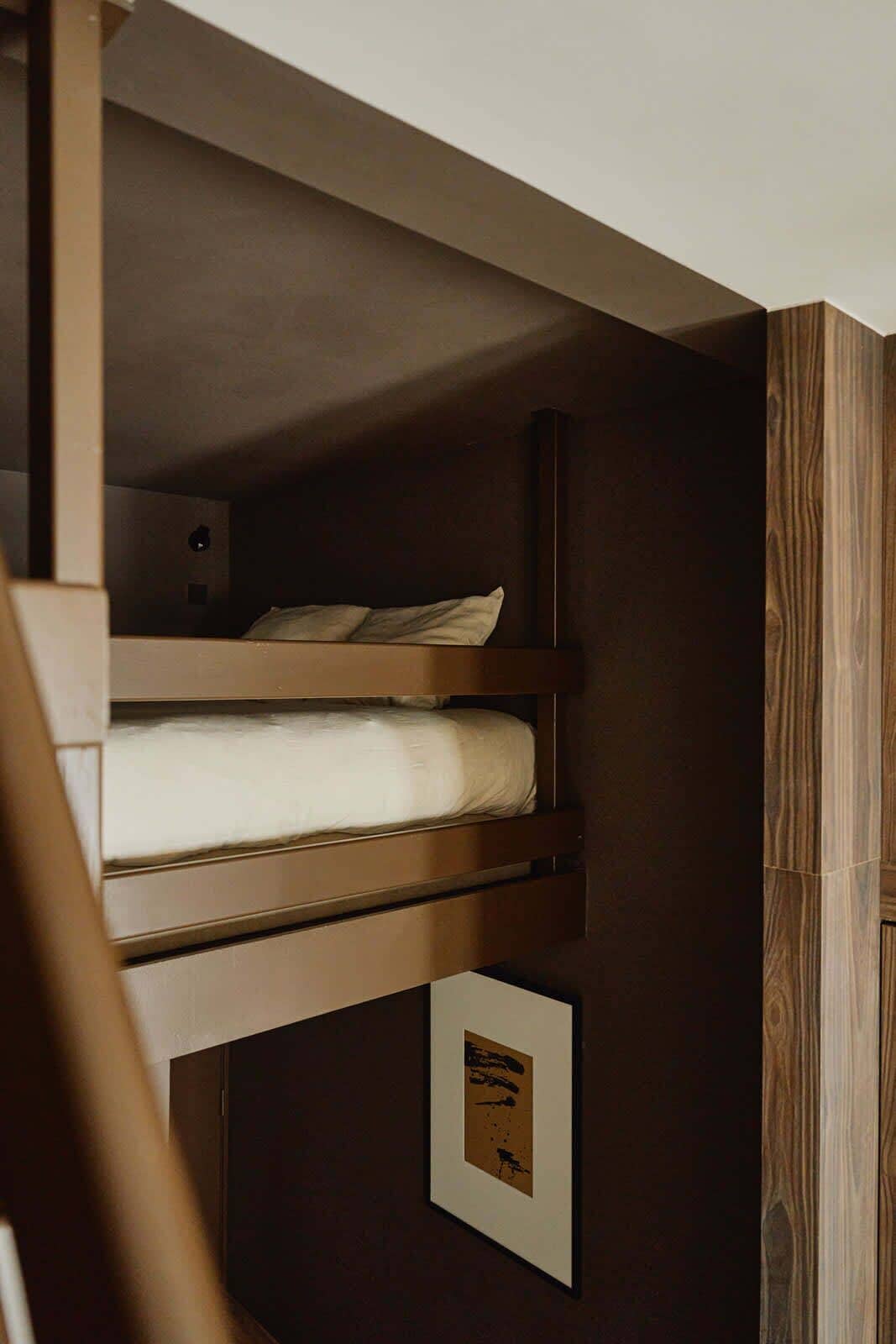 A bunk bed with a framed picture on the wall below.