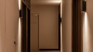 Un pasillo estrecho con alfombra, puertas a ambos lados y otra al final.
