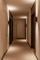 Un pasillo estrecho con alfombra, puertas a ambos lados y otra al final.