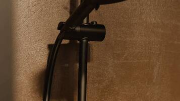 A shower with a handheld attachment and a wall-mounted control panel.