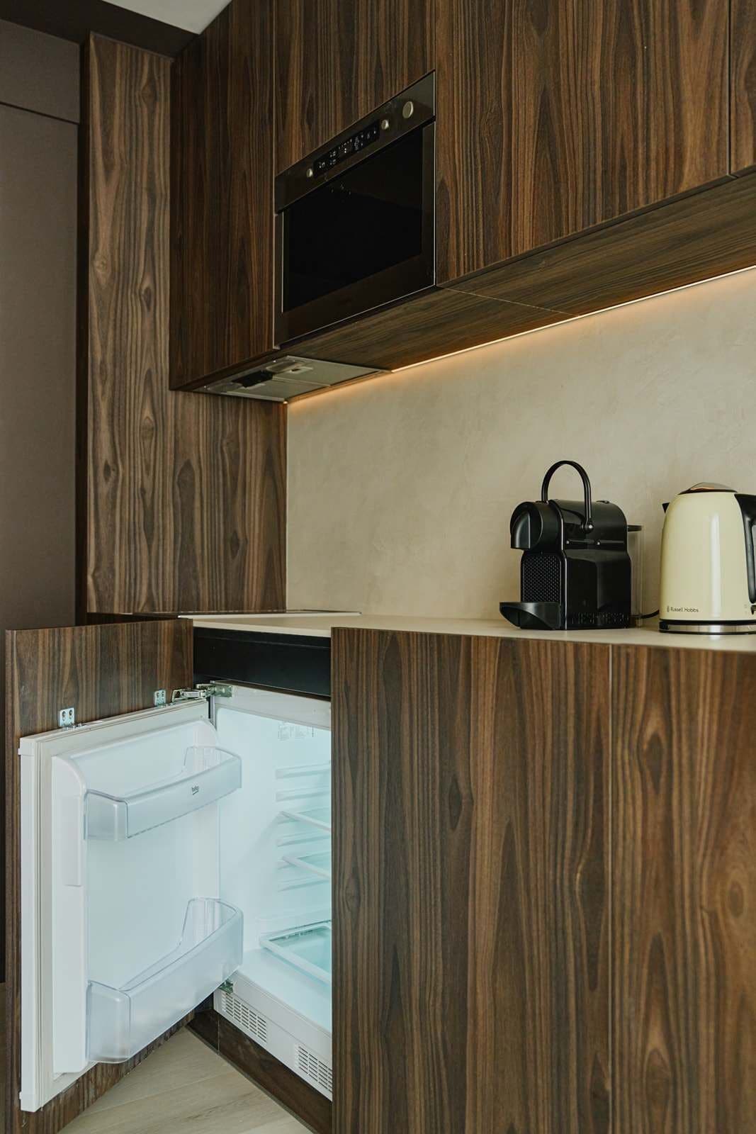 Una cocina moderna con armarios de madera, horno empotrado, hervidor y lavavajillas.