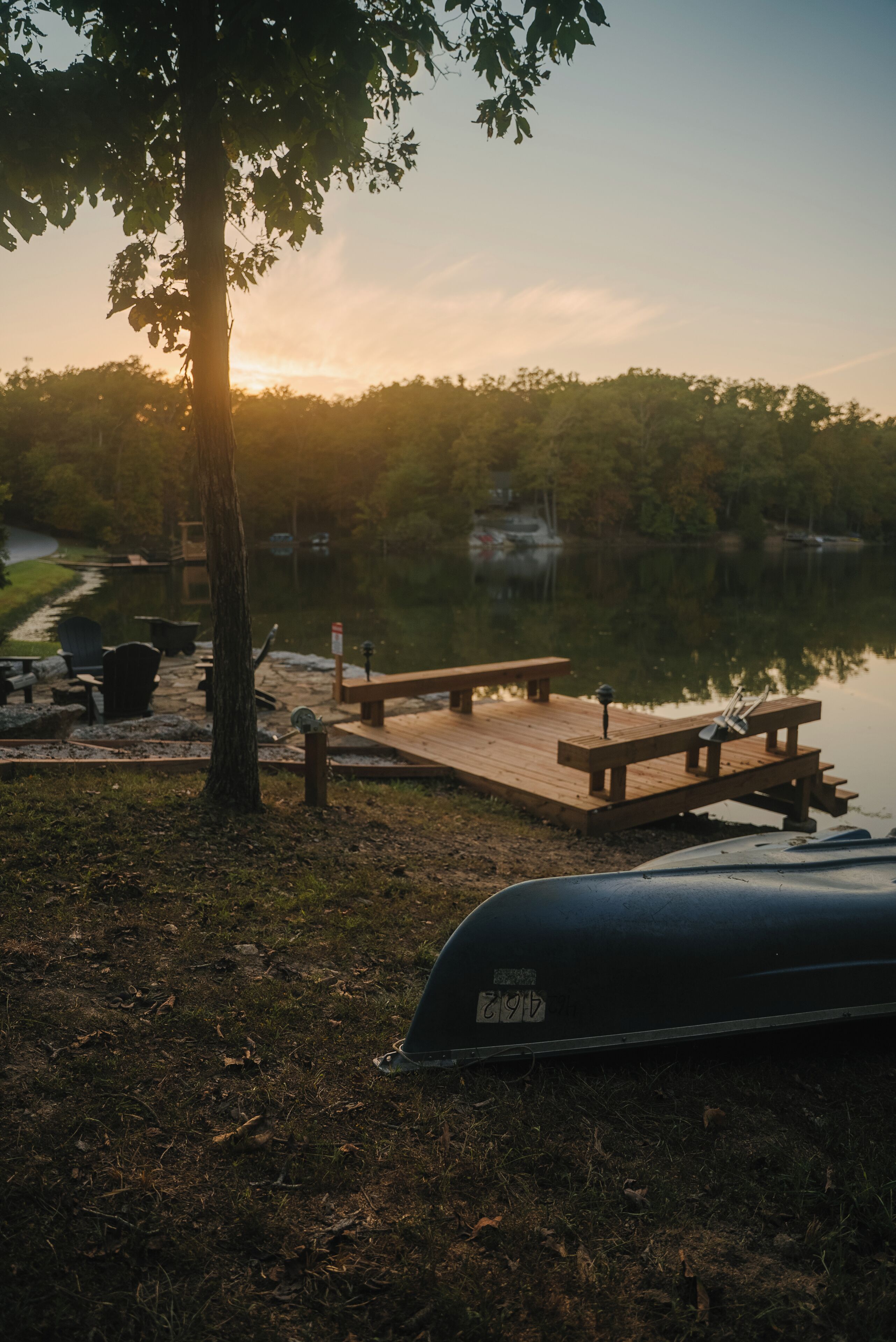 A lakeside picnic area with wooden benches and a grill.
