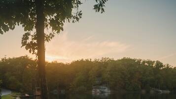 A lakeside picnic area with wooden benches and a grill.