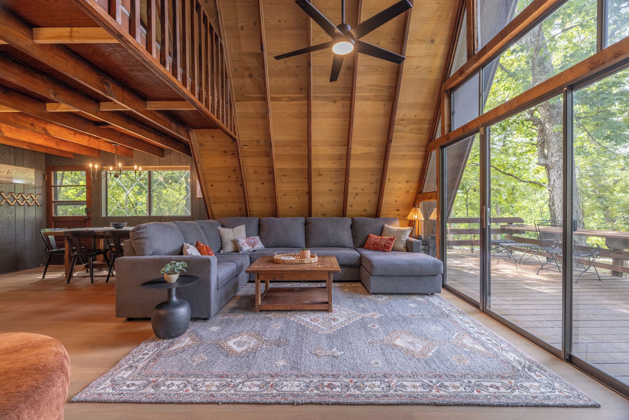 A spacious loft with a large gray sectional sofa, a wooden coffee table, and a patterned rug.