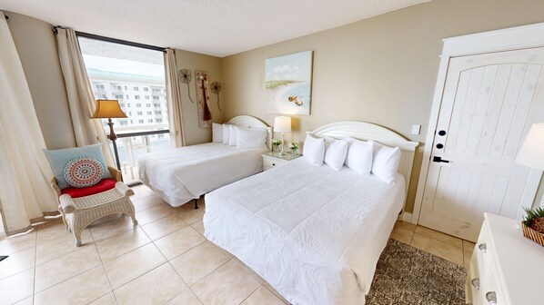 A hotel room with two beds, a chair, a desk, a lamp, and a painting on the wall. - Surfside 0708b 1 Bedroom Condo (Miramar Beach)