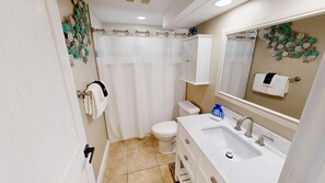 A bathroom with a toilet, sink, and shower curtain. - Surfside 0708b 1 Bedroom Condo (Miramar Beach)