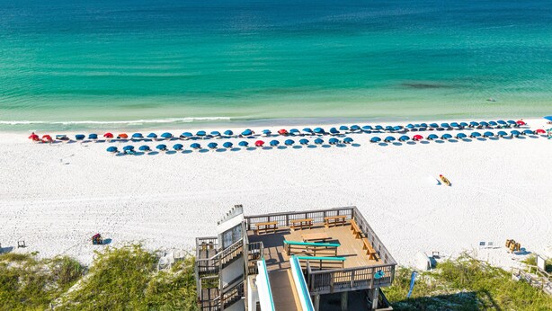 Ein Strand mit Reihen von Sonnenschirmen und Liegestühlen, einem Rettungsturm und freiem Blick auf den Ozean.