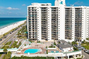 A high-rise hotel with multiple balconies, a pool area, and a beach view. - Surfside 0708b 1 Bedroom Condo (Miramar Beach)