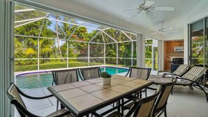 Un patio couvert avec une piscine, un coin repas et une cuisine.