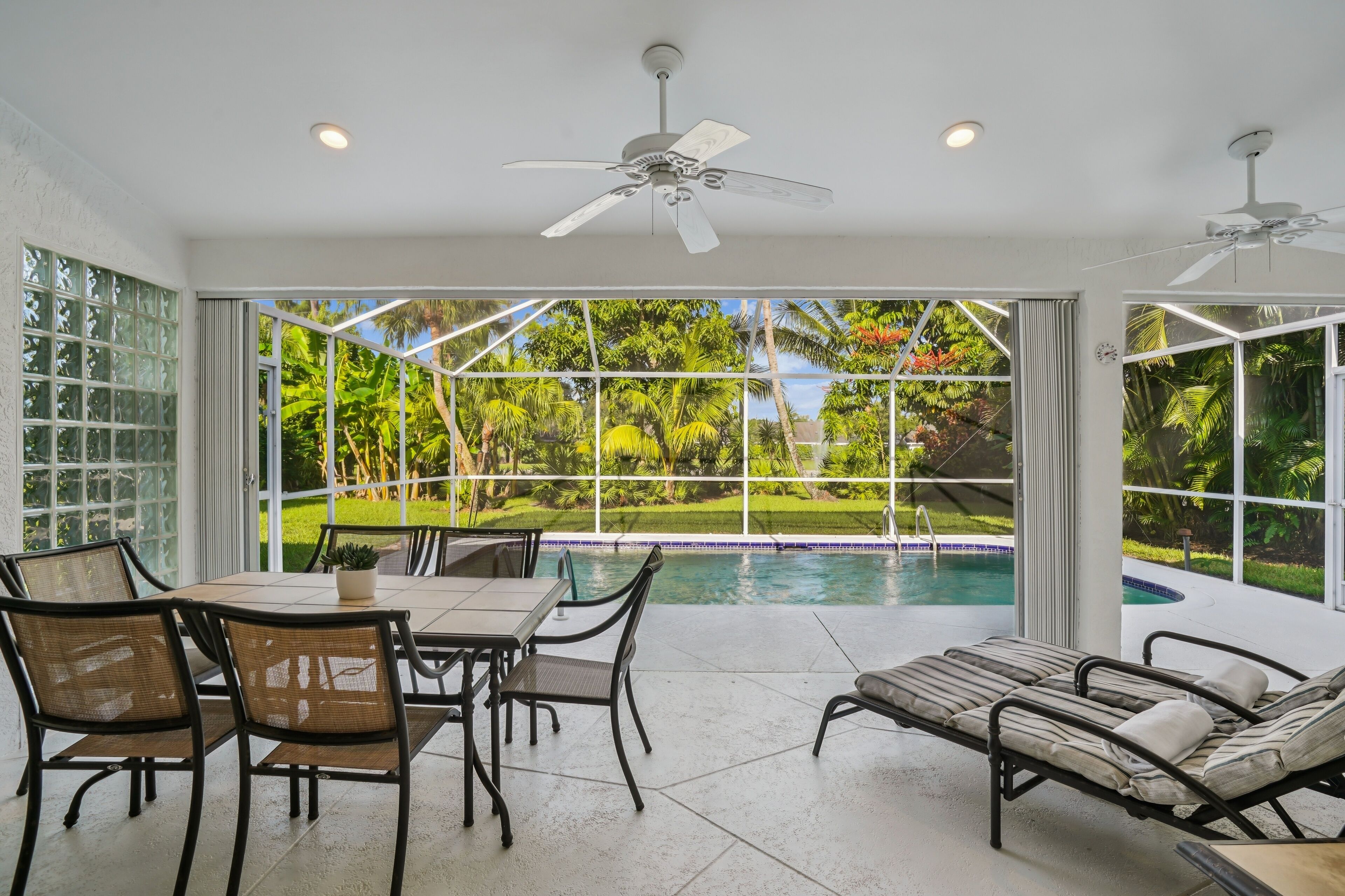 A sunlit patio with a pool, dining area, and lounge chairs.