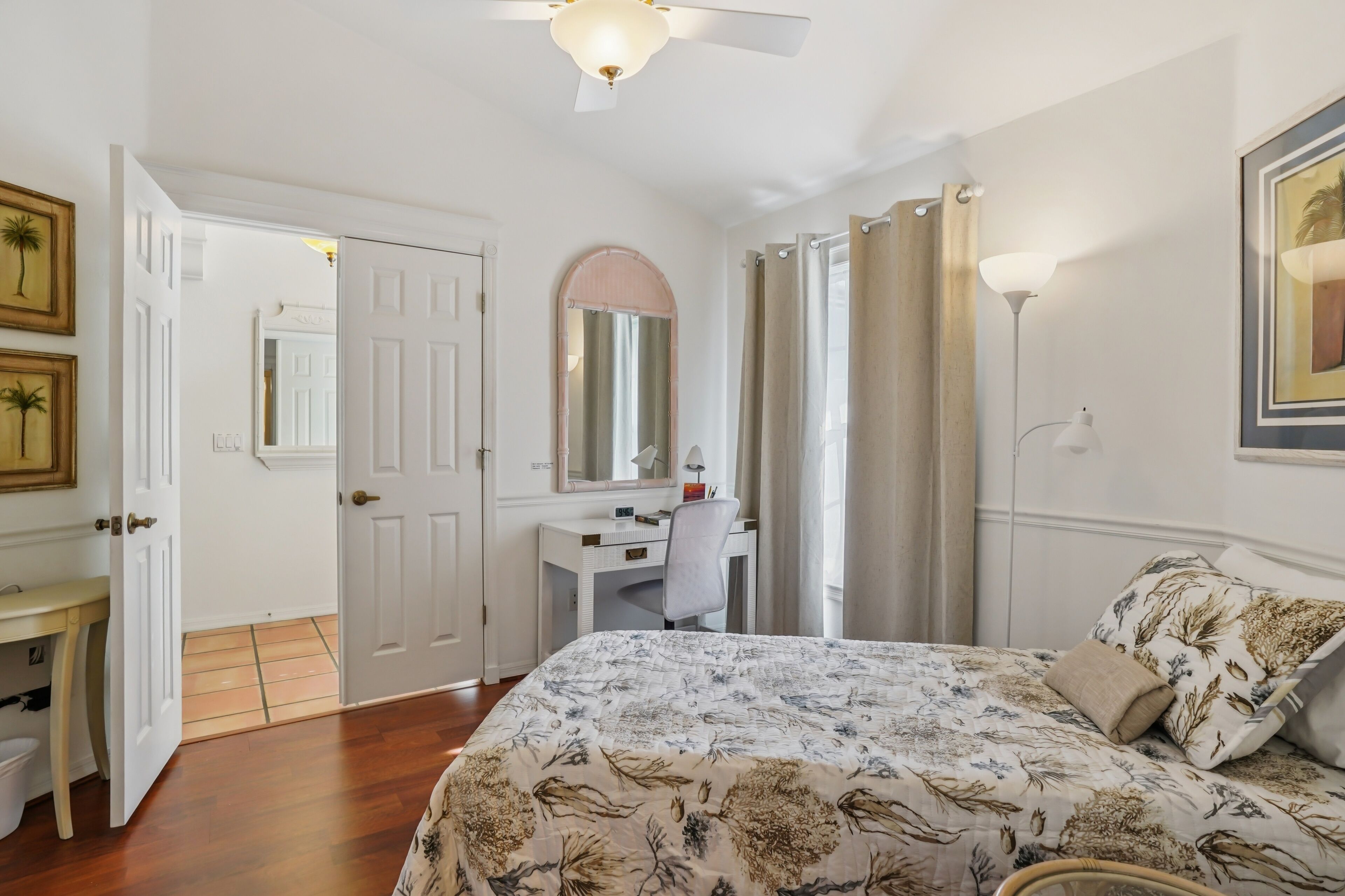 A bedroom with a bed, desk, chair, and a ceiling fan.
