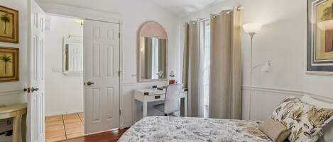 A bedroom with a bed, desk, chair, and a ceiling fan.