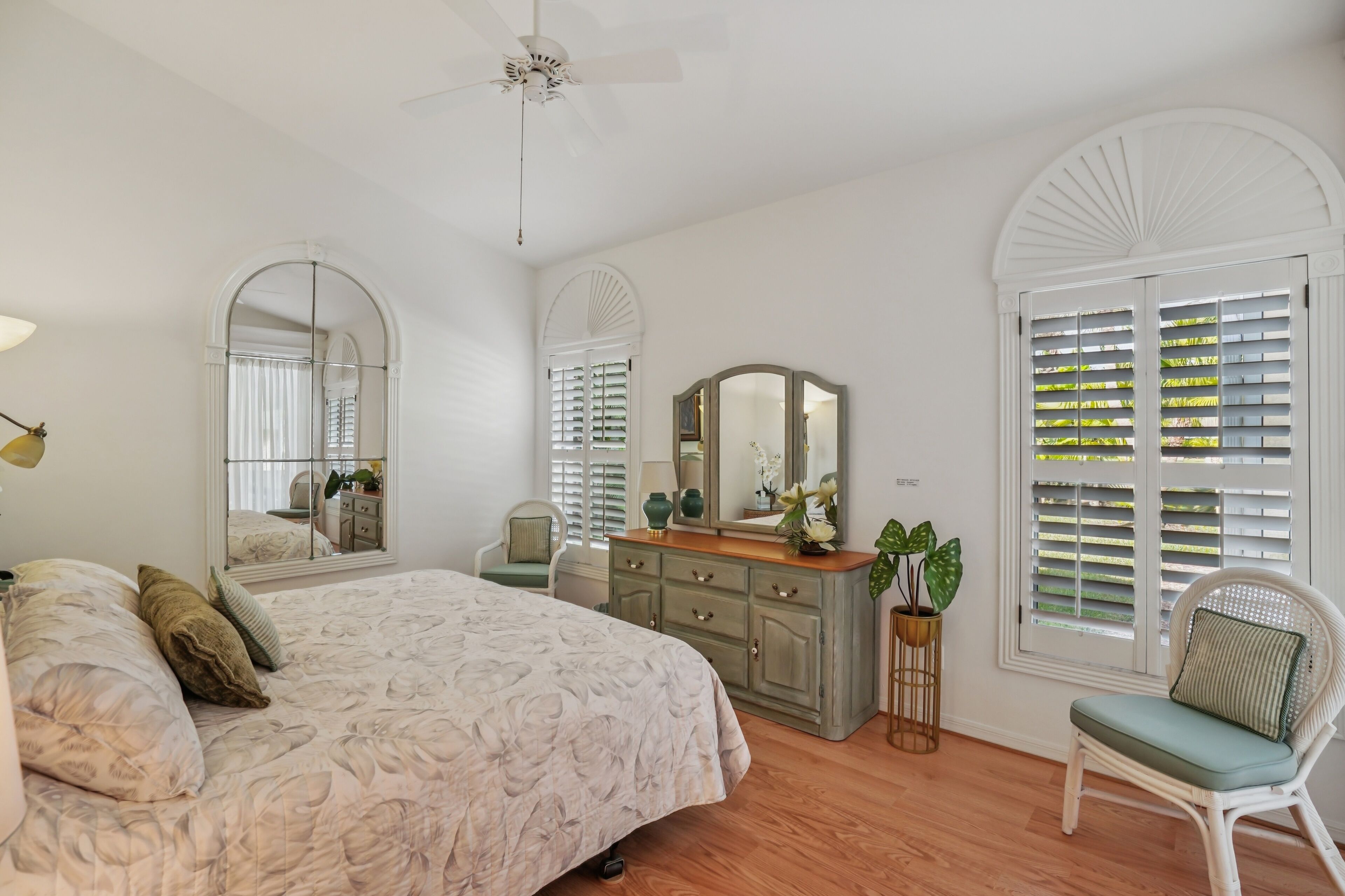 A bedroom with a large bed, a dresser, a chair, and a mirror.