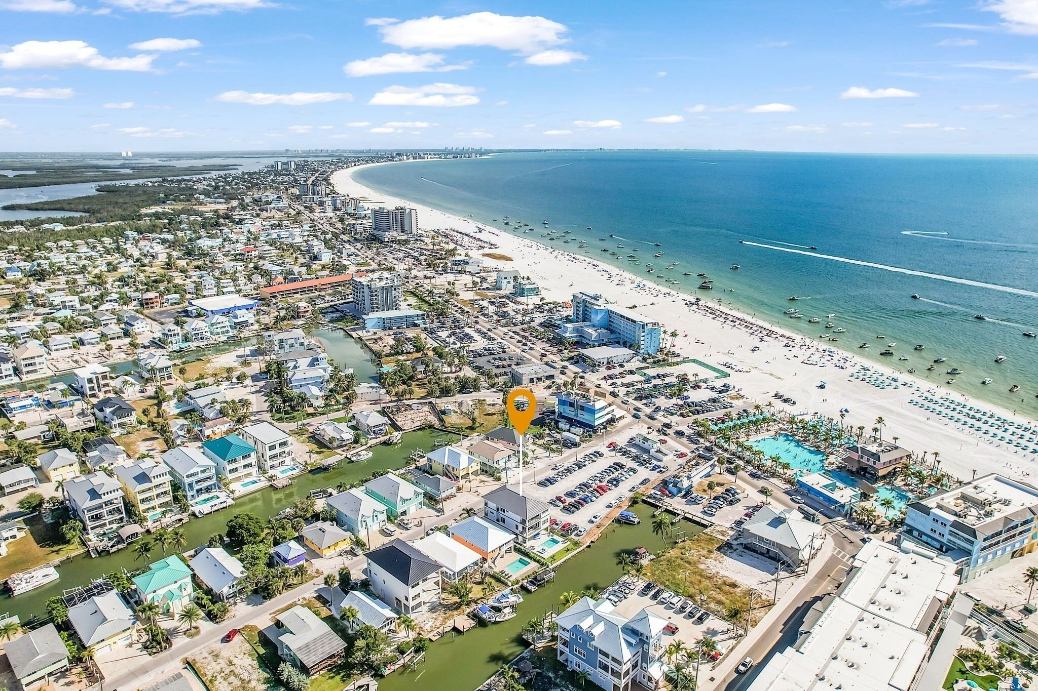 Vista aérea de una ciudad costera con una playa extensa, aguas azules cristalinas y una combinación de edificios residenciales y comerciales.