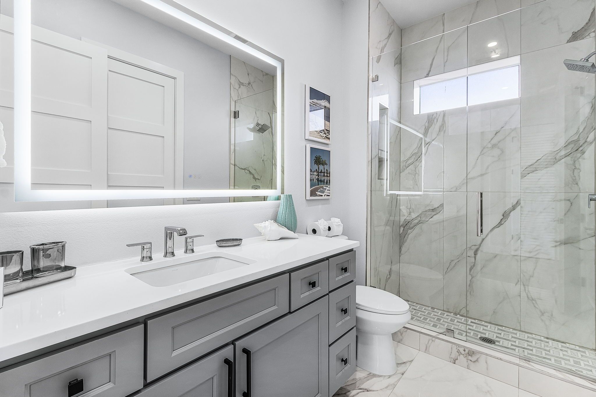 A modern bathroom with a large mirror, a white sink, and a shower area.