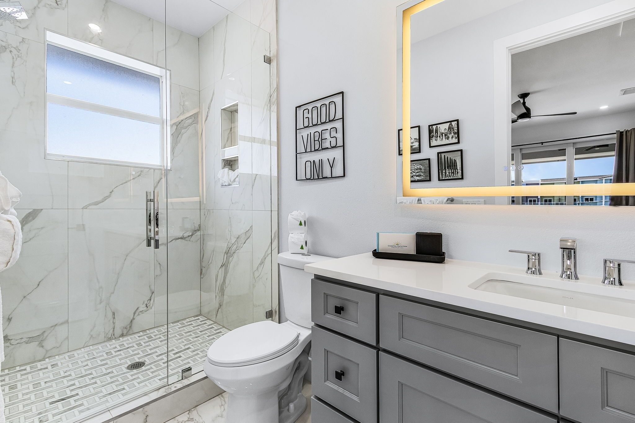Un baño moderno con cabina de ducha de vidrio, inodoro blanco y tocador con espejo.