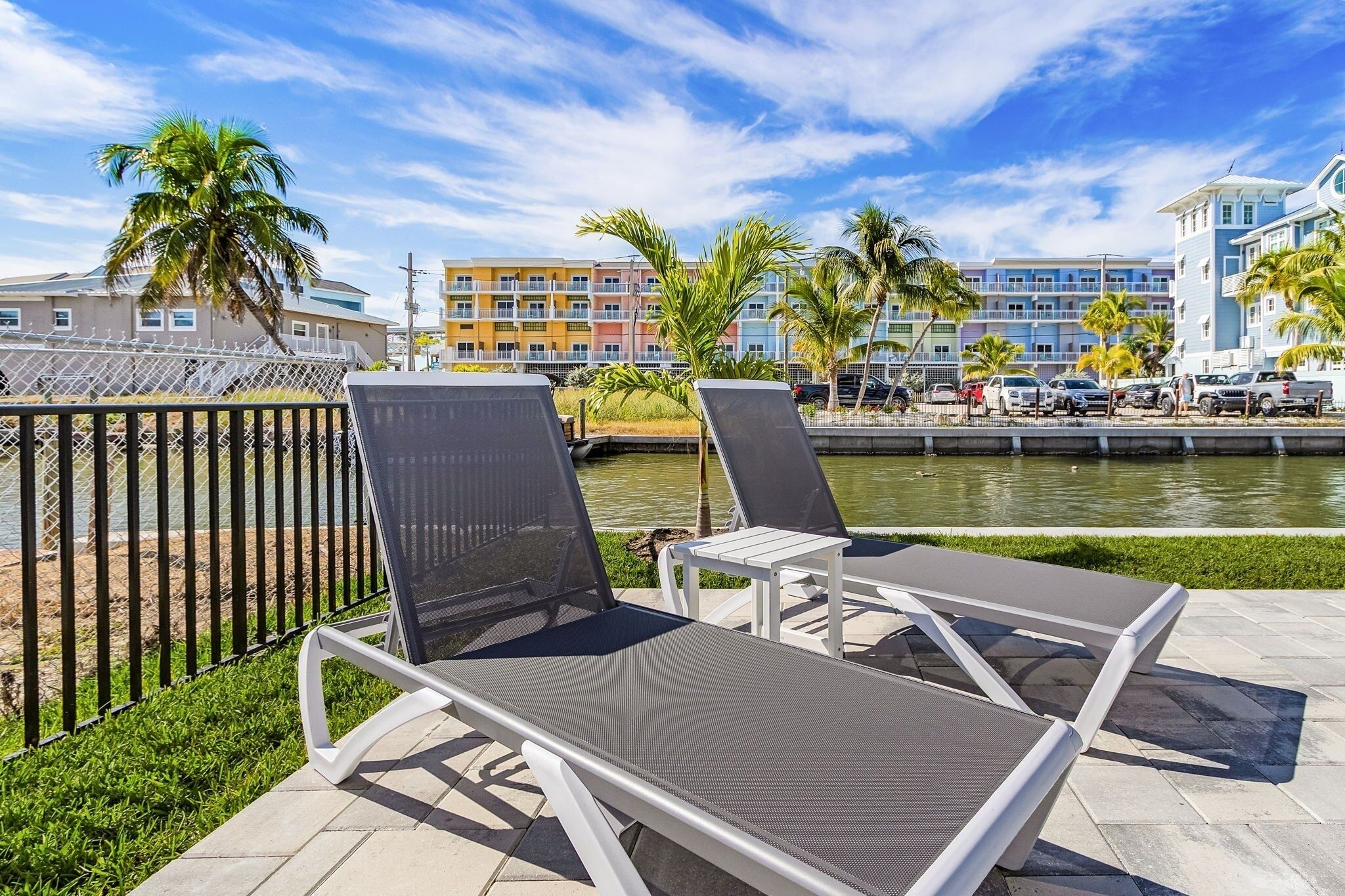 A poolside area with lounge chairs and a view of a water body and buildings in the background.