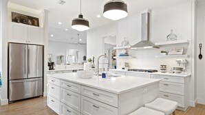 A modern kitchen with white cabinetry, stainless steel appliances, and pendant lighting.