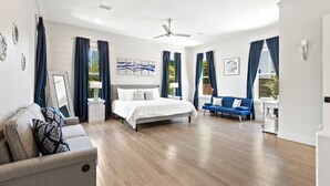 A spacious bedroom with a large bed, a sofa, and a desk.