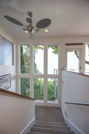 A staircase with a ceiling fan, large windows, and a sign on the wall.