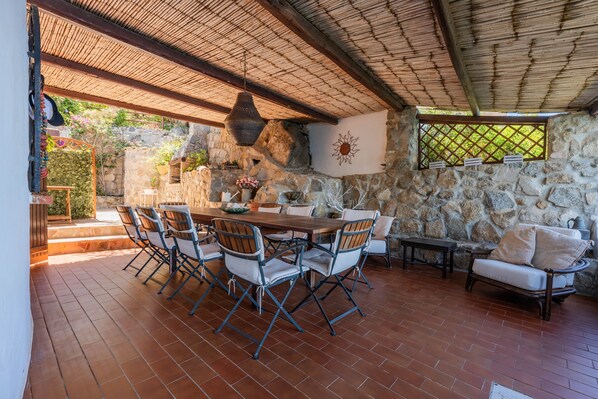 Un patio al aire libre con paredes de piedra, una mesa de madera y sillas.