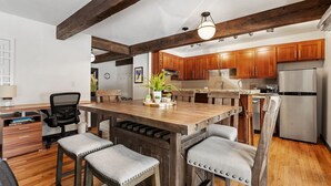 Una cocina con armarios de madera, un refrigerador de acero inoxidable y una isla de madera con taburetes de bar.