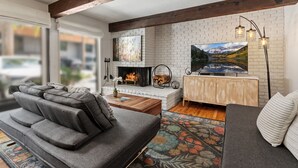 Una sala moderna con chimenea, televisor grande y una zona de estar acogedora.