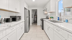Una cocina moderna con armarios blancos, electrodomésticos de acero inoxidable y encimera de mármol.