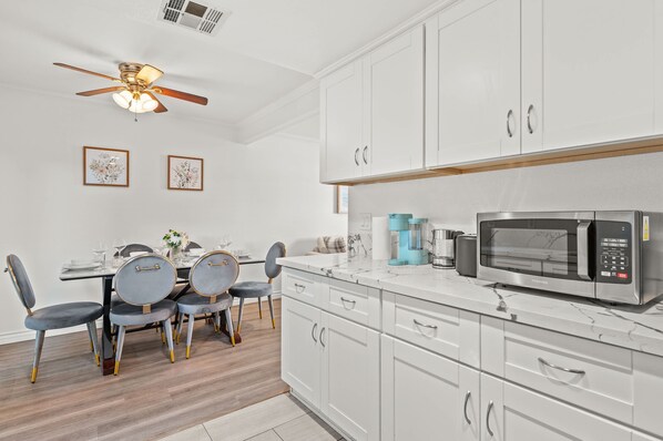 Una cocina moderna con gabinetes blancos, microondas y ventilador de techo.