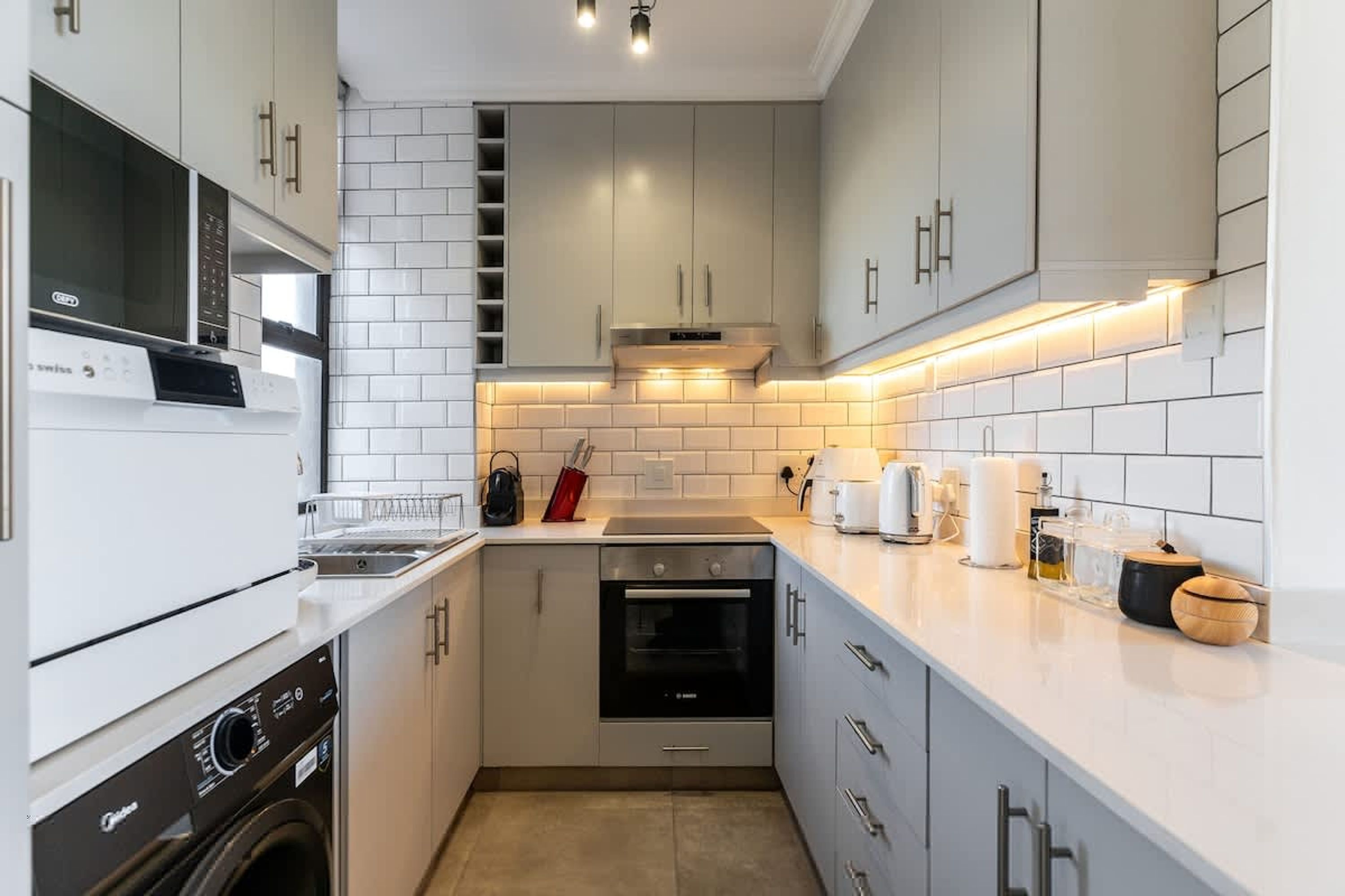 A compact kitchen with white cabinets, a built-in oven, a microwave, and a dishwasher.
