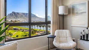 Habitación de hotel con un amplio ventanal que ofrece vistas a una montaña y un paisaje urbano.
