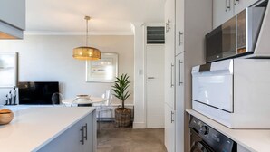 Una cocina moderna con armarios blancos, un microondas integrado y una lavadora.
