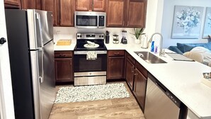 Une cuisine moderne avec des meubles en bois, des appareils en acier inoxydable et un plan de travail blanc.