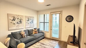 Un salon moderne avec un canapé gris, une table basse et un téléviseur posé sur un meuble.