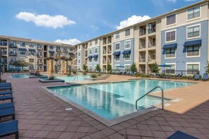 A multi-story residential building with a central swimming pool, outdoor seating, and a clear sky. - Casa Bloom! WFH friendly , very close proximity to everything FUN in Frisco! (Frisco)