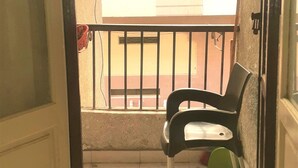 Une porte ouverte donnant sur un balcon équipé d’une chaise et d’une rambarde.