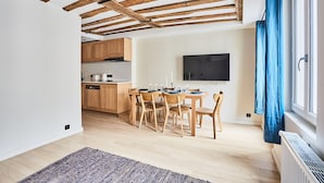 A modern kitchen with wooden cabinets, a dining area with a table set for four, and a large window with blue curtains. - Flat Terrace Centre de Paris Bourse (Paris)