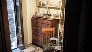 Eine gemütliche Küche mit einem Holzkasten, einem Stuhl, einem kleinen Tisch und einem Fenster.